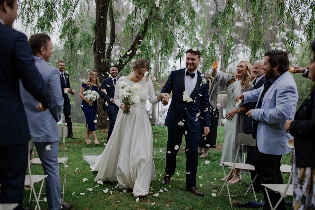 Bride and Groom walking down the aisle as confetti is thrown on them